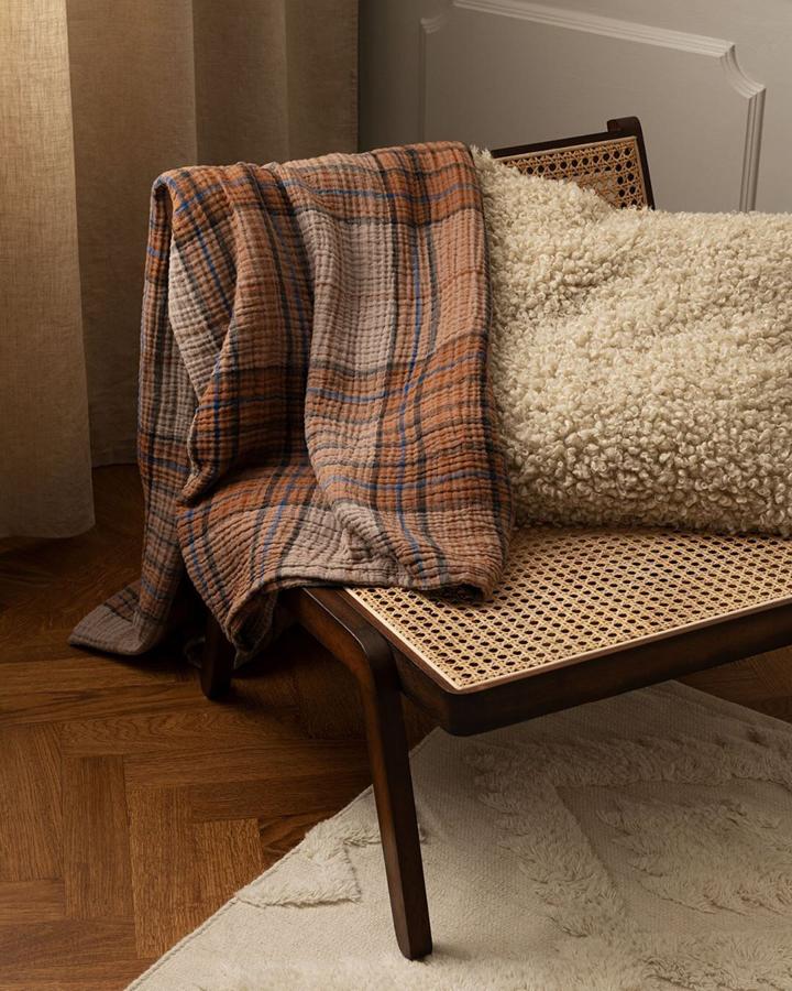 Esta manta de muselina suave de algodón con diseño de cuadros en tonos tierra es de H&M Home y cuesta 89.99 euros.