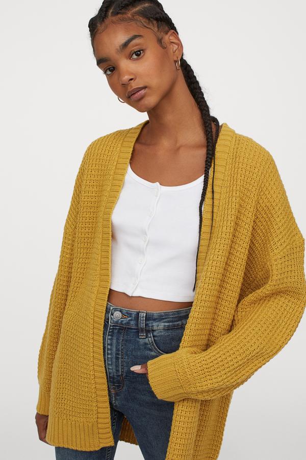 Este cárdigan en punto suave con textura está disponible en amarillo oscuro o en negro. Con hombros marcadamente caídos y ribete de canalé en abertura, puños y bajo, es de H&M y tiene un precio de 19,99 euros.