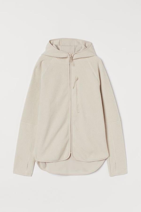 En tejido polar suave termoaislante con capucha y cremallera delante, esta chaqueta ligera está disponible en color beige y negro y viene con mangas raglán con abertura para el pulgar, bolsillo superior con cremallera y bajo redondeado asimétrico. Tiene un precio de 29,99 euros y estará disponible entre las tallas XS y XL.