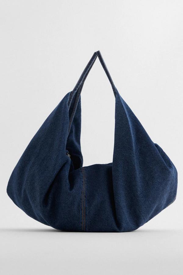 En formato maxi, este bolso tipo saca en azul denim cuenta con cuerpo con pliegues en los laterales y asas de hombro. Con interior forrado con bolsillo, es de Zara y tiene un precio de 29,95 euros.