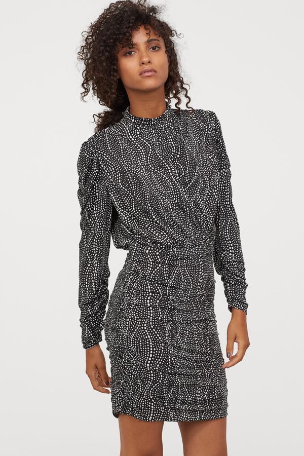 En color negro con estampado blanco, este vestido entallado en punto drapeado cuenta con manga larga y cuello elevado. Tiene un precio de 34,99 euros.