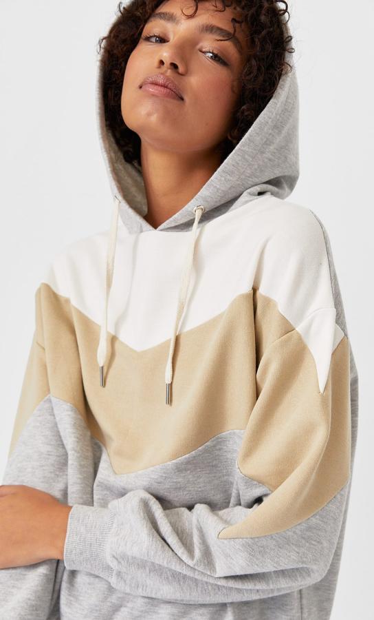 Para las que buscan una versión más deportiva y relajada de esta tendencia tonal Stradivarius tiene esta sudadera con capucha y manga larga en color gris con bloques en beige y crudo. Tiene un precio de 25,99 euros y está disponible entre las tallas XS y XL, menos en la S que ya se ha agotado.