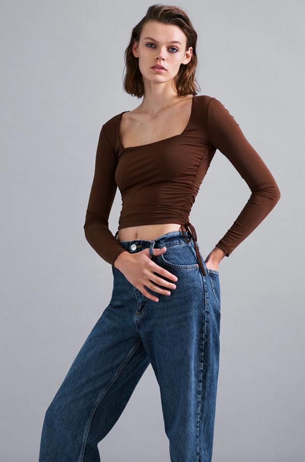 Confeccionado en mezcla de poliamida, este top de Zara en marrón chocolate viene con escote cuadrado, manga larga y bajo con frunces laterales ajustables con cordones. Tiene un precio de 15,95 euros y está disponible en las tallas S, M y L.