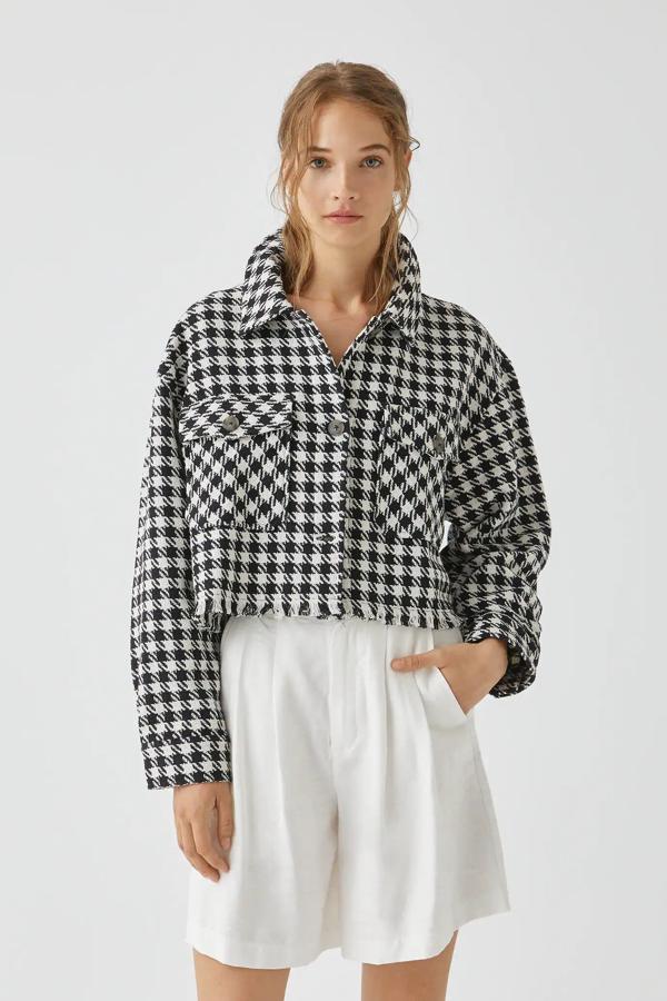 Con cuadros en blanco y negro, esta sobrecamisa cropped con bolsillos delanteros y detalle de flecos en el bajo es de Pull & Bear y tiene un precio de 29,99 euros.