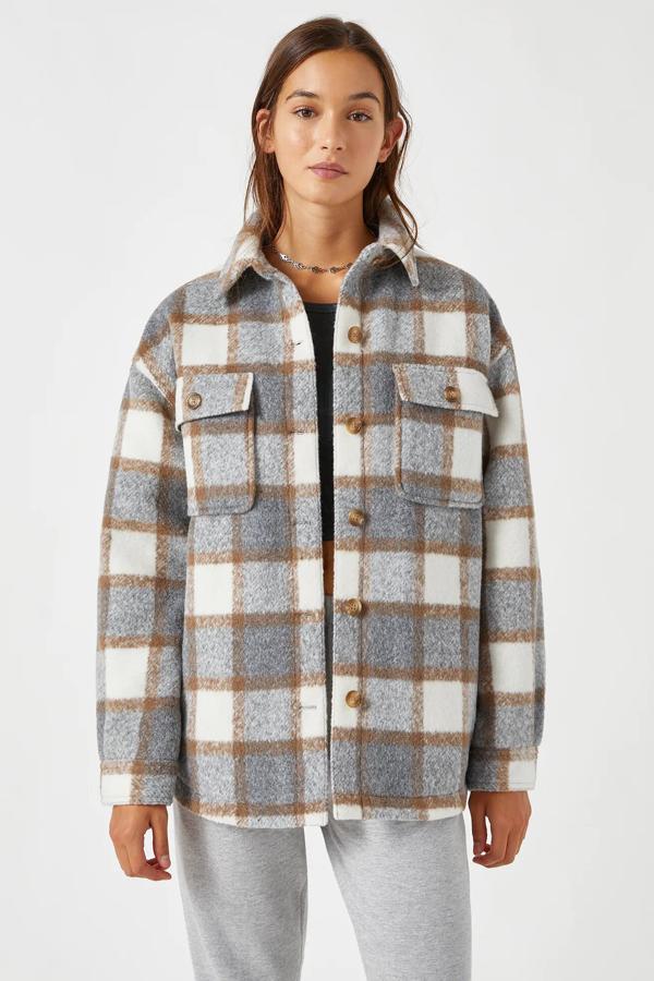 En tonos grises, camel y blanco, esta sobrecamisa con estampado de cuadros cuenta con bolsillos delanteros y cierre mediante botones. Es de Pull & Bear y tiene un precio de 35,99 euros.