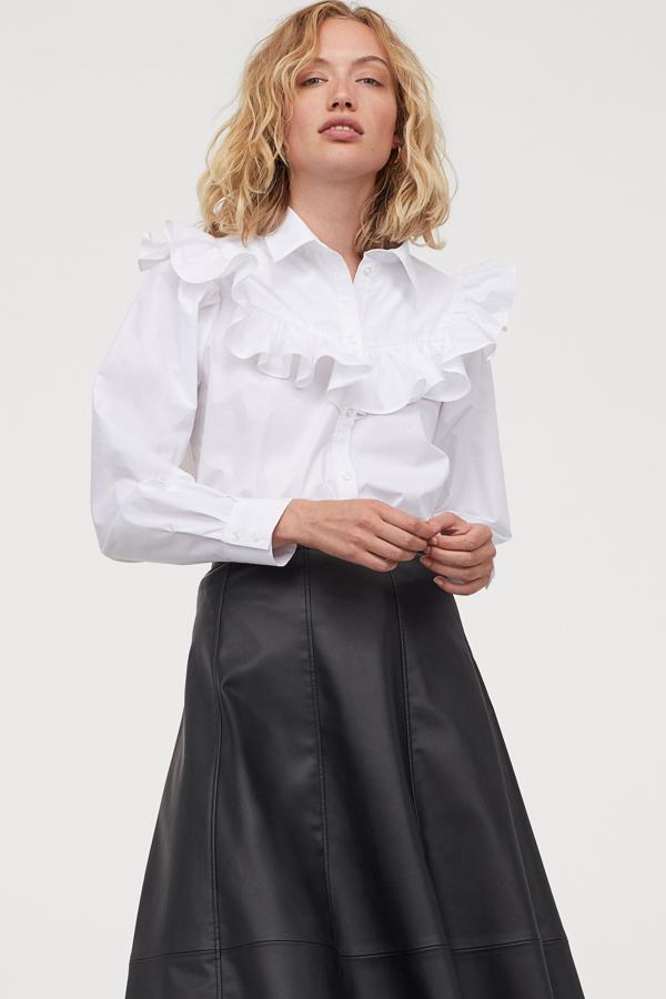 Esta blusa blanca de algodón con volante en la parte delantera hasta los hombros cuenta con bajo redondeado y tiene un precio de 19,99 euros. Es de H&M.