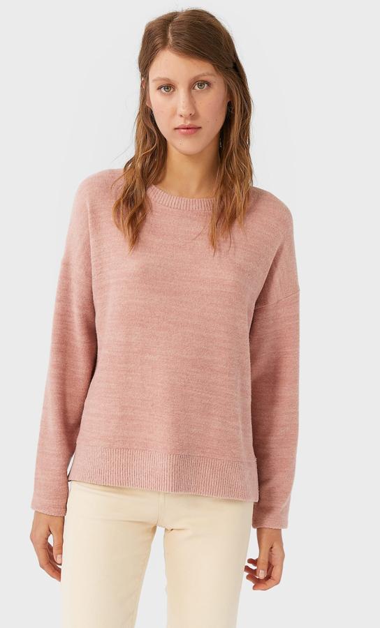Con cuello redondo y mangas largas, este jersey de Stradivarius en rosa empolvado tiene detalles de aberturas laterales y un precio de 15,99 euros. Está disponible entre las tallas XS y L.
