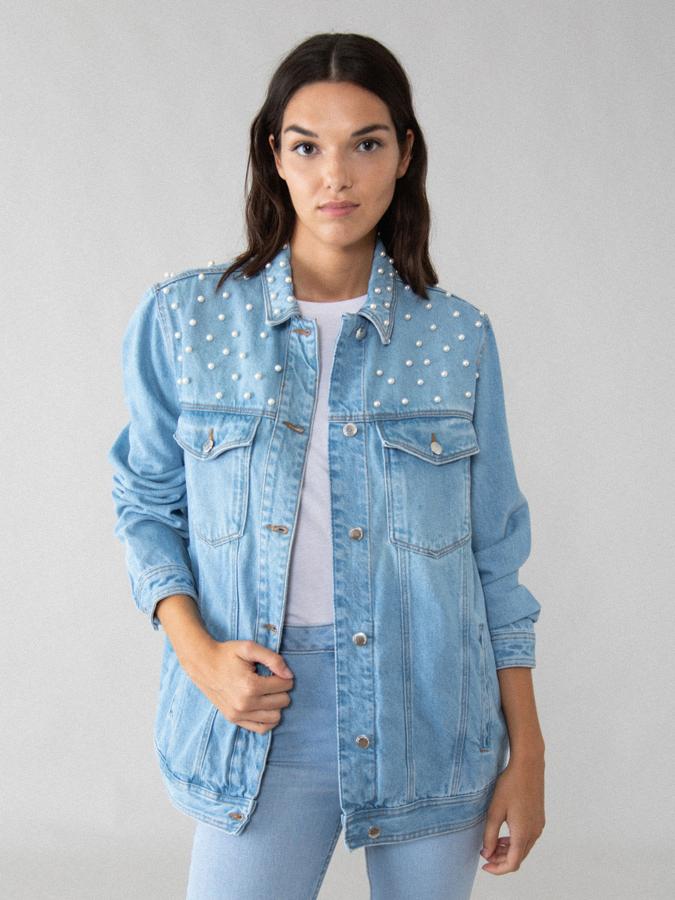 De corte oversize, con bolsillos delanteros y cierre de botones metálicos, esta cazadora vaquera de Lefties con efecto lavado viene con apliques de perlas en los hombros. Con un precio de 29,99 euros solo está disponible en la talla S.