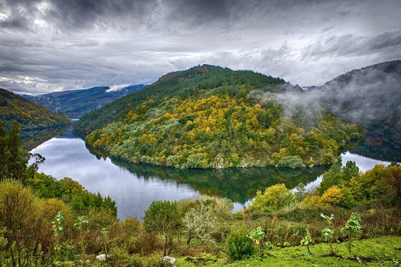La Ribeira Sacra tiene de todo: profundos valles, ríos caudalosos, viñedos casi verticales, preciosos pueblos y exuberantes bosques. Uno de los lugares más espectaculares de este rincón de Galicia es el Cabo do Mundo, el pronunciado meandro que dibuja el río Miño a su paso por los municipios de Chantada y O Saviñao. Y con los colores del otoño se vuelve, directamente, sublime. Desde el mirador de A Cova tendrás una panorámica excepcional de este maravilloso rincón de Galicia.