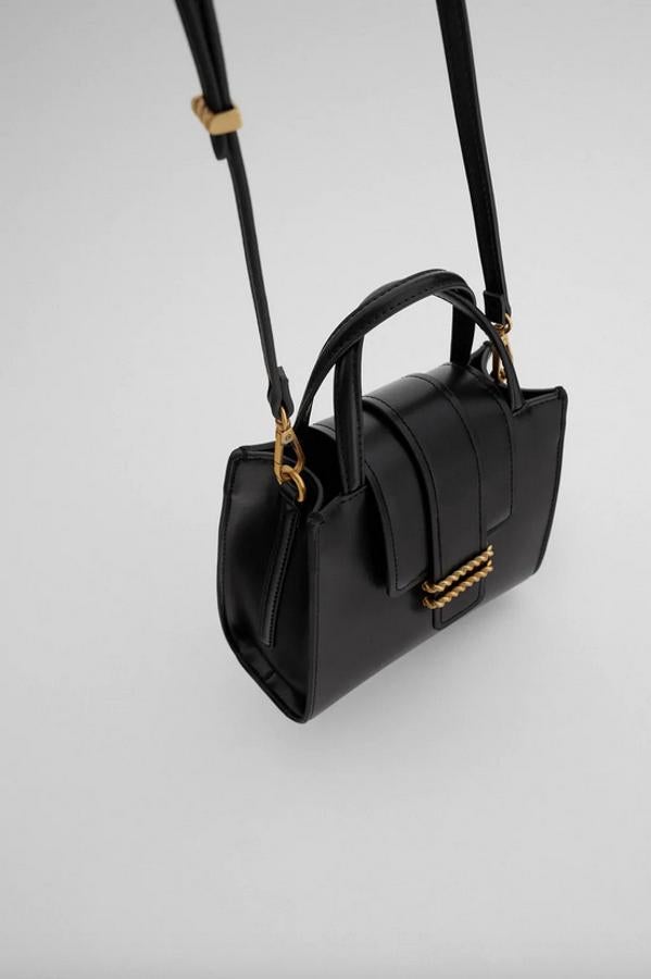 Formato city para este bolso negro con detalle de cordón dorado doble en la solapa. Con asas de mano y de hombro, ajustable y extraíble, costaba 25,95 euros y está disponible por 15,99 euros.