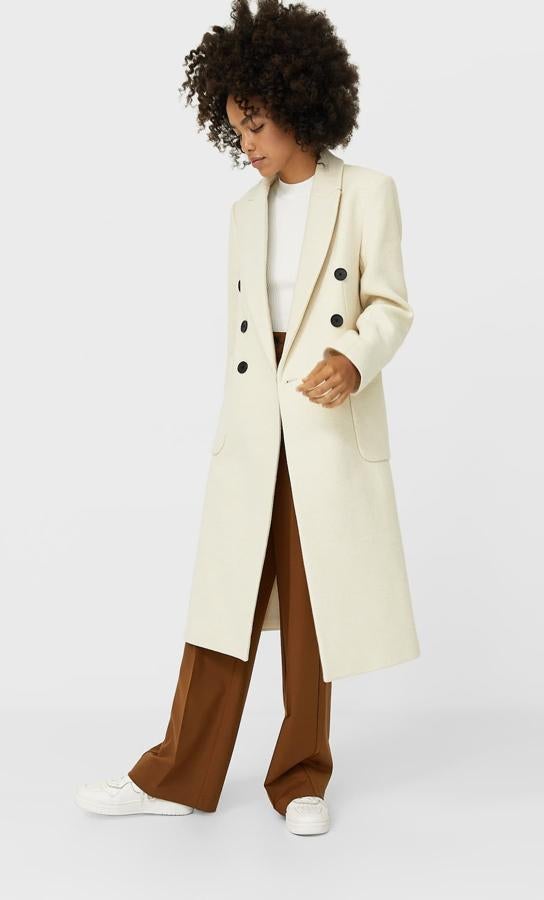 El de Stradivarius es largo y masculino, con botones oscuros y bolsillos vistos (59,99 euros).