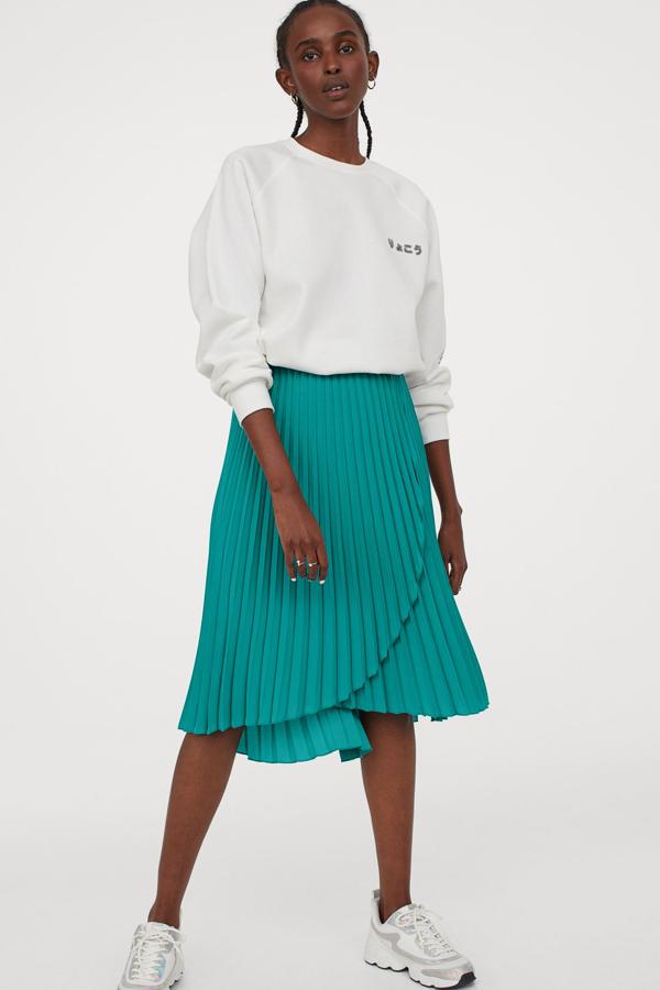 Esta falda midi plisada en color turquesa también está disponible en negro o fucsia. Con frente cruzado, cuenta con elástico revestido en la cintura y ribetes sobrehilados. Tiene un precio de 24,99 euros.