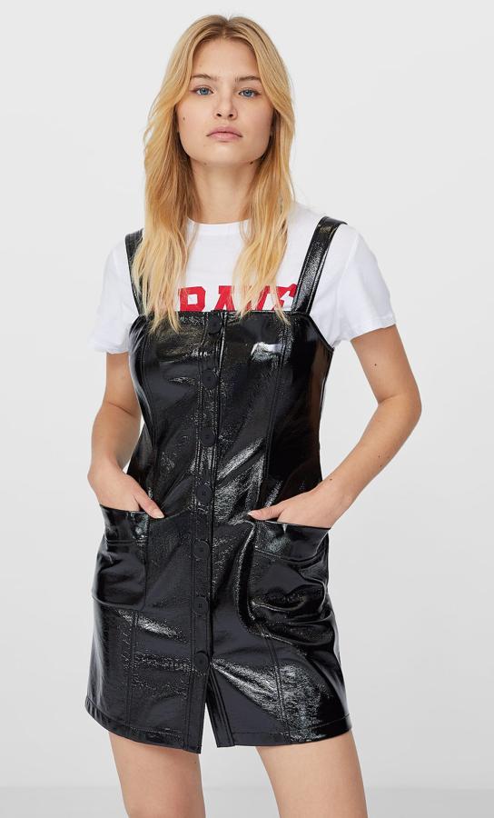 Este pichi de vinilo en color negro con escote cuadrado y tirantes cuenta con bolsillos en la parte delantera y tiene un precio de 25,99 euros.