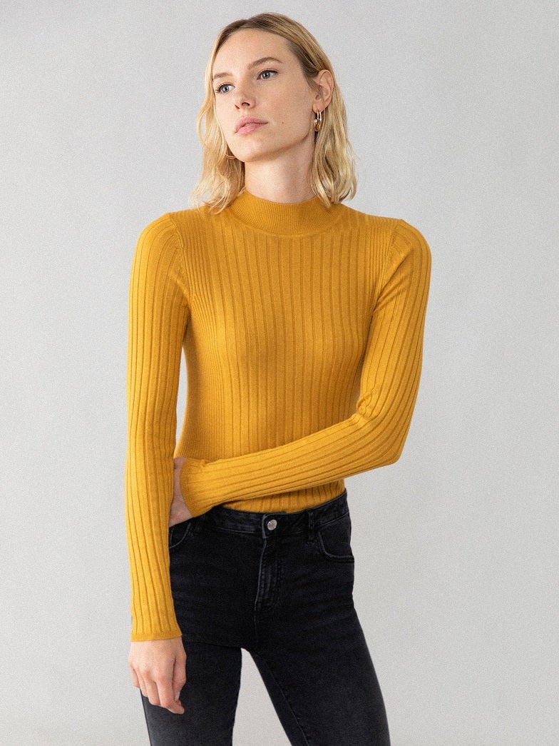 En versión ajustada y con cuello perkins, jersey de punto canalé en mostaza. Disponible también en otros cinco colores para combinar con todo. (8,99 euros).