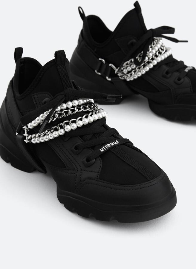 Cadenas y perlas extraíbles para estas deportivas elaboradas en corte de piel de vacuno e inserciones de tejido en color negro, con cordones a tono. Cuestan 99 euros y solo quedan en los números 41 y 42.