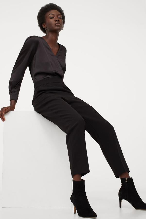 Cuerpo cruzado y ligeramente drapeado en crepé de satén para este mono negro de H&M con escote de pico delantero y trasero, mangas tres cuartos con pliegues y botones metalizados en los piño. Tiene perneras tobilleras con raya ajustadas en el bajo, tiene un precio de 49,99 euros y solo se vende en la web de la firma, entre las tallas 32 y 50.
