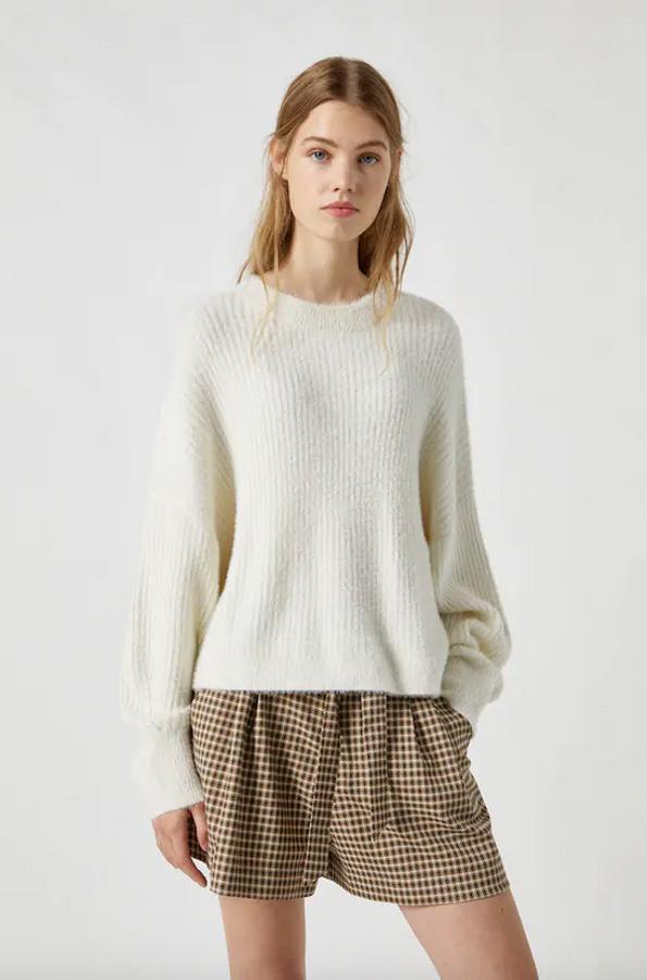 Este jersey de canalé de pelo corto, con cuello redondo y manga larga está disponible en color crudo y breva entre las tallas XS y L. Cuesta 22,99 euros.