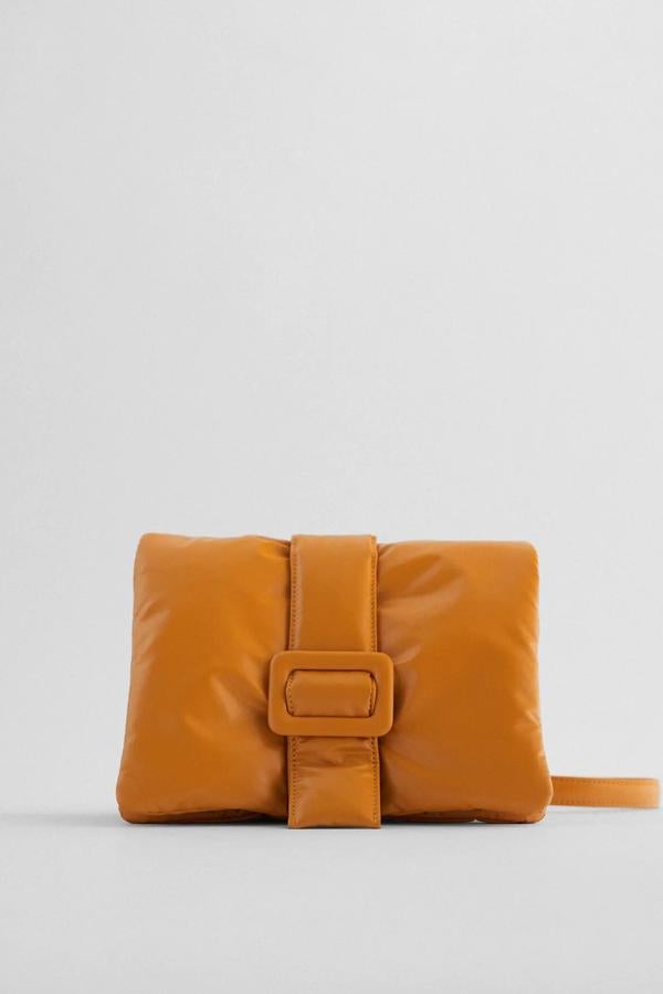 En color naranja, este bolso formato bandolera cuenta con cuerpo acolchado con detalle de hebilla y asa de hombro con cadena. Tiene un precio de 25,95 euros.
