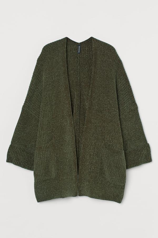 En color verde caqui, este cárdigan oversize en punto de chenilla suave está también disponible en beige. Con mangas amplias con puños vueltos y bolsillos delanteros, tiene un precio de 29,99 euros.
