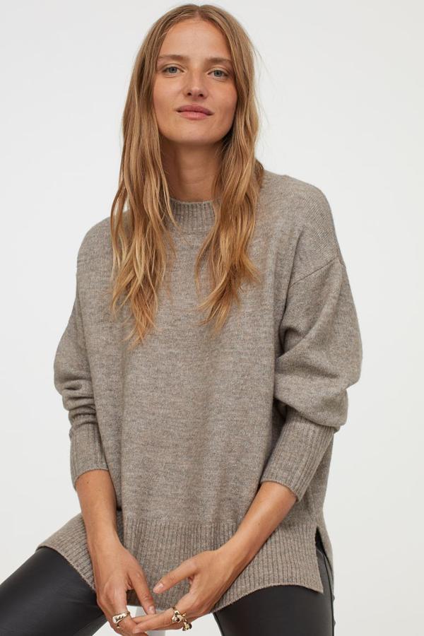 Con cuello redondo, hombros caídos, aberturas laterales y bajo asimétrico, este jersey de punto suave con lana en la trama tiene ribete de canalé en cuello, puños y bajo y está disponible en beige grisáceo, gris hielo y gris jaspeado entre las tallas XS y XXL por 19,99 euros.