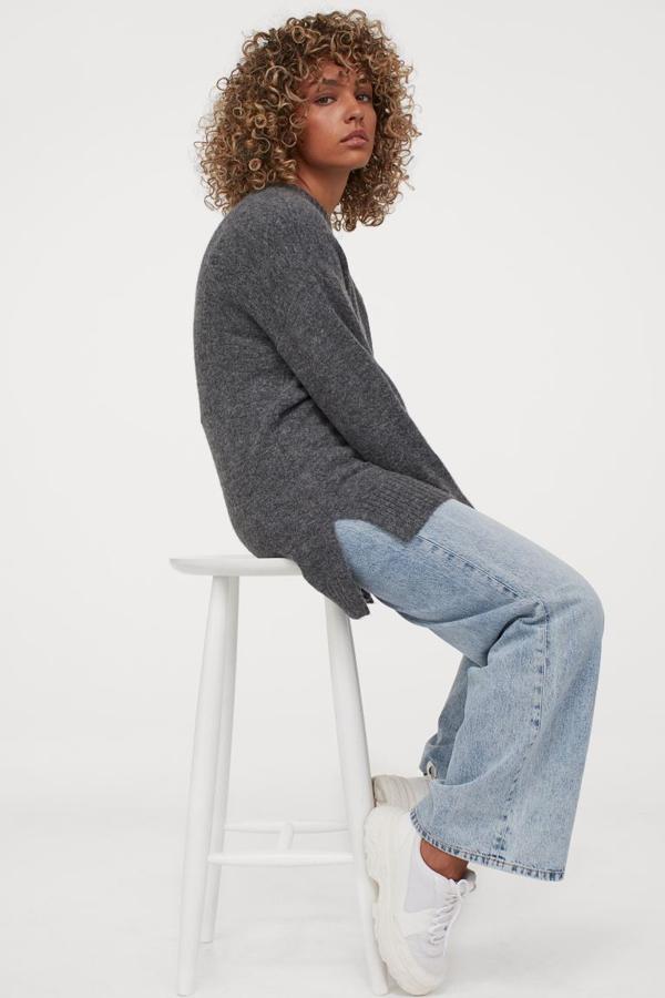 Disponible en beige o gris oscuro jaspeado, este jersey de punto suave con lana en la trama viene con hombros caídos con ribete de canalé en el cuello, puños y bajo, con aberturas laterales y espalda algo más larga. Confeccionado con poliéster reciclado, cuesta 19,99 euros y está disponible entre las tallas XS y XL, pero en gris solo quedan las dos primeras.