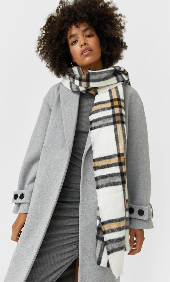 Fondo blanco con estampado de cuadros en negro, beige y gris para esta bufanda de Stradivarius con acabado desflecado que tiene un precio de 12,99 euros.