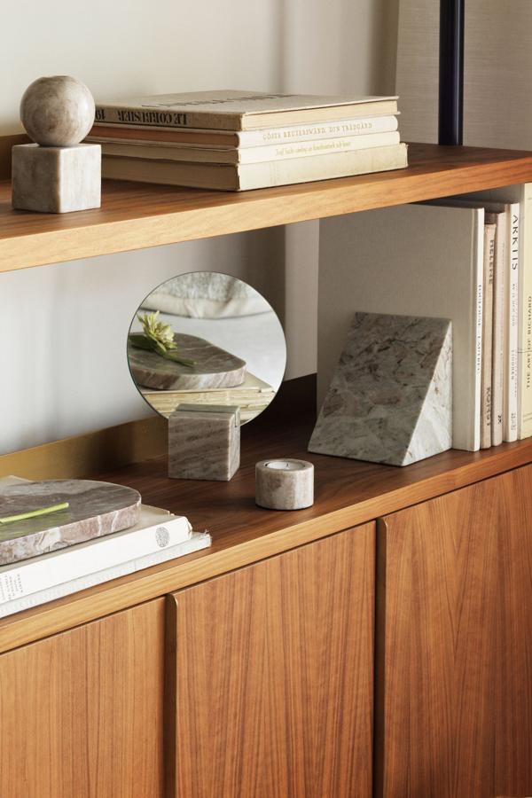 Cuando pienses en espejos no mires solo a tus paredes: pueden ser lo que tu estantería necesita para que parezca más grande. Usa piezas como esta de H&M Home, un pequeño espejo redondo encastrado en un bloque de mármol y conseguirás un efecto muy elegante (24,99 euros).