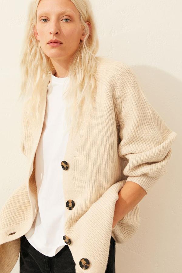 En punto de canalé suave con lana en la trama, este cárdigan en beige claro confeccionado con poliéster reciclado viene con diseño cuadrado con escote de pico, botones delanteros a contraste y mangas amplias ceñidas en los puños. Tiene un precio de 19,99 euros y está disponible únicamente en la talla XS.