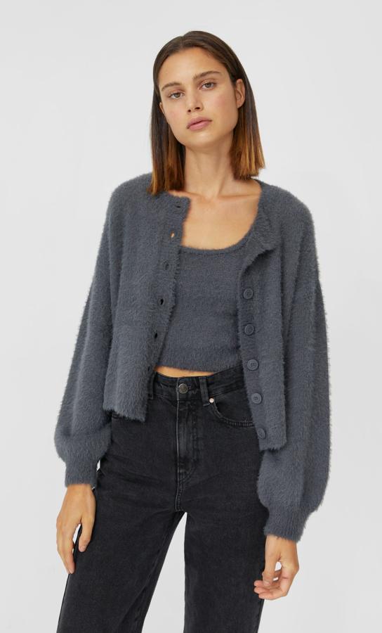 Confeccionado en tejido de tacto suave, este cárdigan de Stradivarius viene con cuello redondo, mangas largas y cierre frontal con botones a tono. Podemos encontrarlo en beige, gris marengo, azul y crudo entra las tallas XS y L por 19,99 euros.