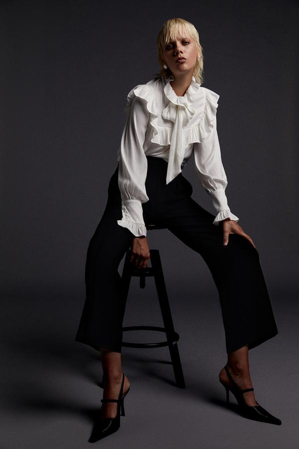 Camisa de manga larga con detalles de volantes y lazada al cuello, de Sfera (29,99 €).