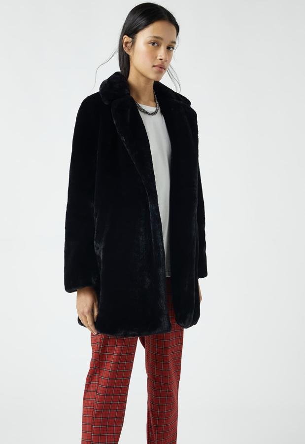 Este abrigo largo de pelo negro con cuello amplio y cierre de botón delantero es de Pull & Bear y tiene un precio de 35,99 euros.