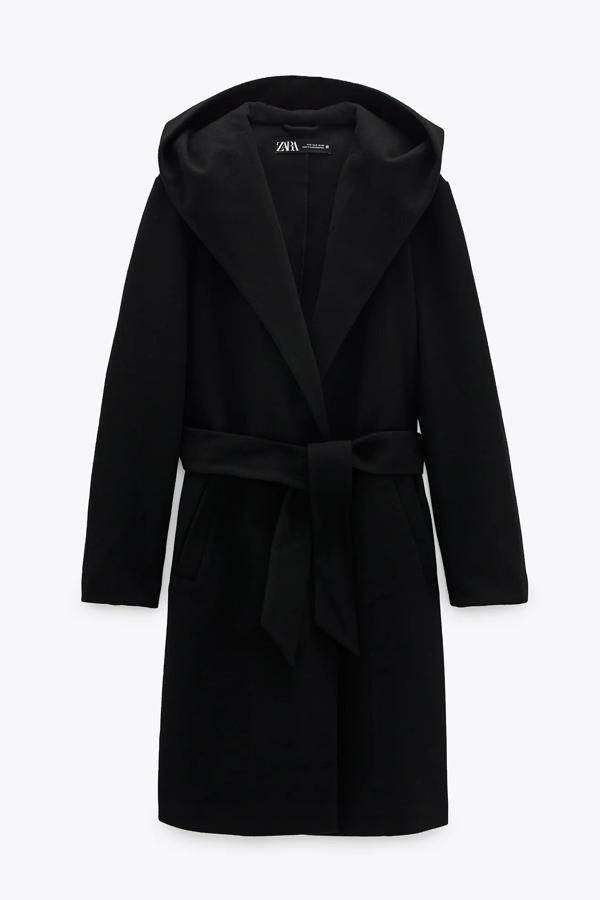 En color negro, este abrigo de cuello subido con capucha y bolsillos frontales cuenta con cierre con cinturón del mismo tejido y tiene un precio de 39,95 euros. Es de Zara.