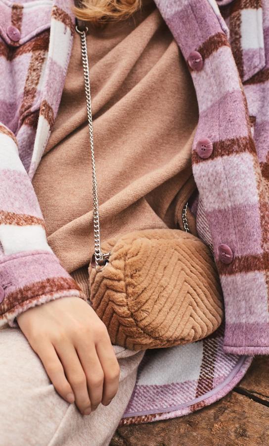 Esta mini bandolera de Stradivarius en color beige viene con correa de cadenas metalizada y cierre superior de cremallera. Cuesta 12,99 euros.