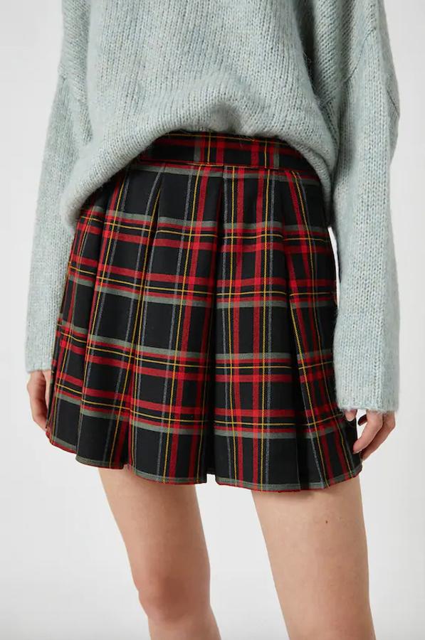 Confeccionada en tejido ligeramente elástico, esta falda corta de fondo negro con estampado de cuadros en tonos rojos es de Pull&Bear y tiene un precio de 19,99 euros. Está disponible entre las tallas XS y XL.