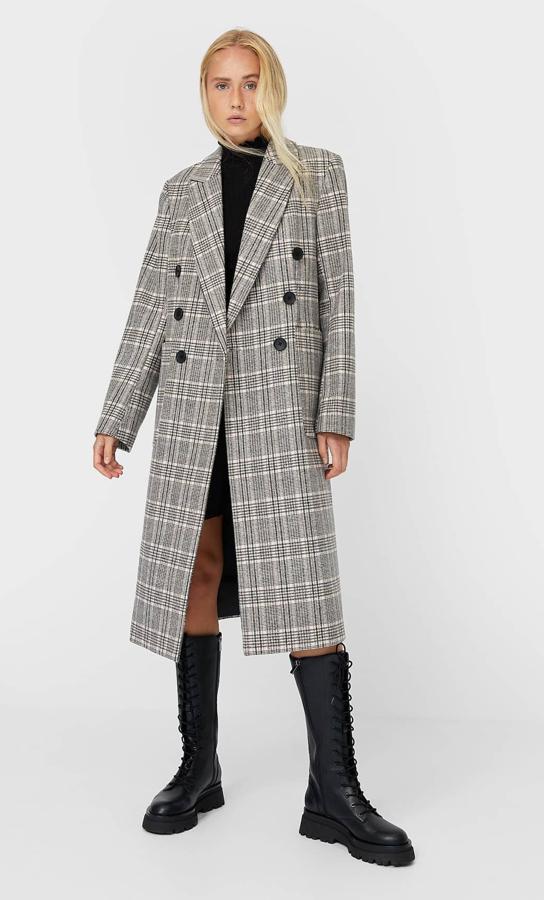 De cuadros en tonos grises, este abrigo largo con cierre frontal mediante botones está también disponible en crudo. Es de Stradivarius y está rebajado a 41,99 euros.