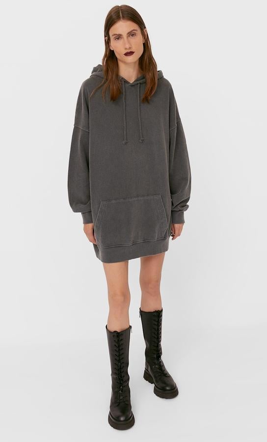 En color gris marengo, este vestido corto de felpa tipo sudadera cuenta con capucha y detalle de bolsillo en el frontal. Tiene un precio de 19,99 euros.