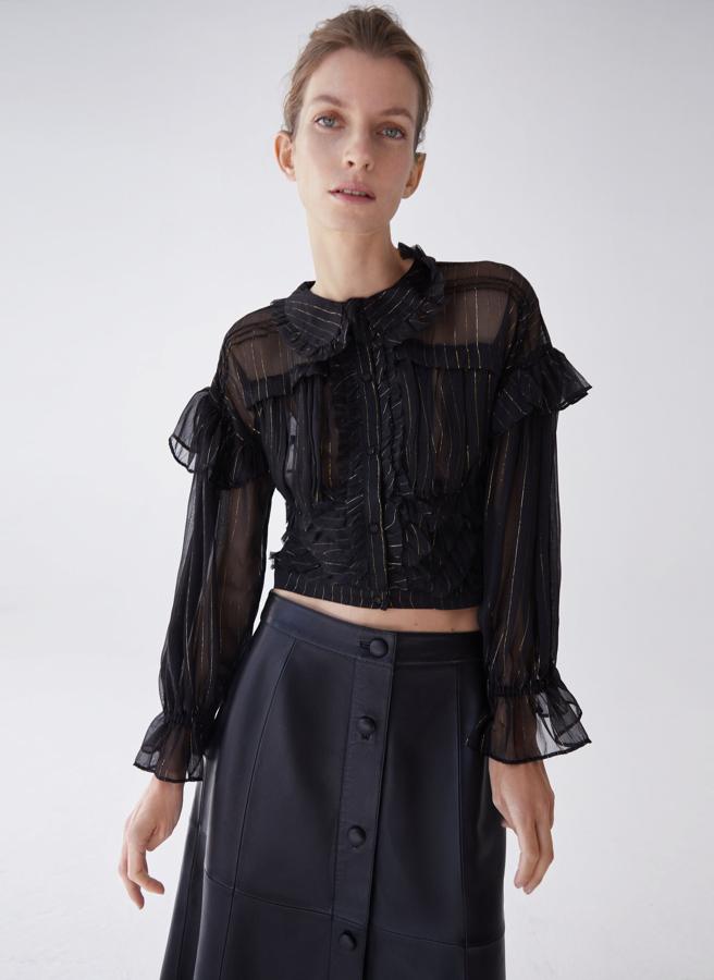 Diseño cropped para esta camisa negra de lúrex con cuello redondo acabado en volante, fruncido en el delantero y construcción tipo fajín. Con cierre frontal de botones ocultos con tapeta, ha pasado de 79 euros a 59,25 y podemos encontrarla en las tallas XS, S y M.