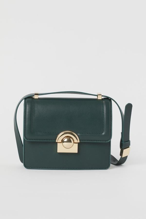 De venta exclusiva en la web de H&M, este bolso bandolera en piel sintética en verde sintética viene con correa ajustable, solapa con cierre a presión metalizado en dorado y un compartimento interior. Cuesta 24,99 euros.