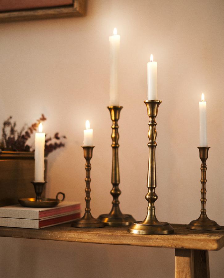 Este candelabro de metal en color oro con efecto envejecido mide 11x31x11 centímetros y tiene un precio de 25,99 euros.