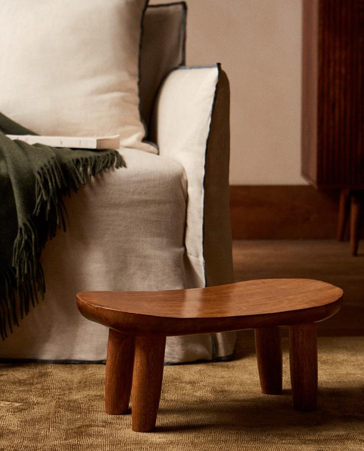 Con asiento arqueado y cuatro patas, este taburete bajo de madera de mango con medidas de 25x20x44 centímetros tiene un precio de 39,99 euros.
