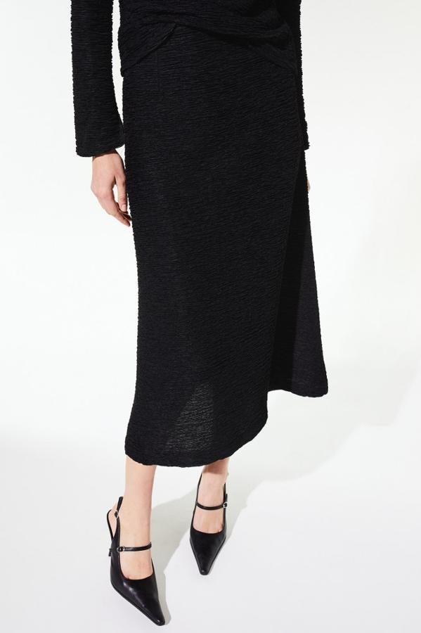 Diseño midi para esta falda negra con bajo evasé y tejido de textura que tiene un precio de 25,99 euros y podemos encontrar en las tallas S, M y L.