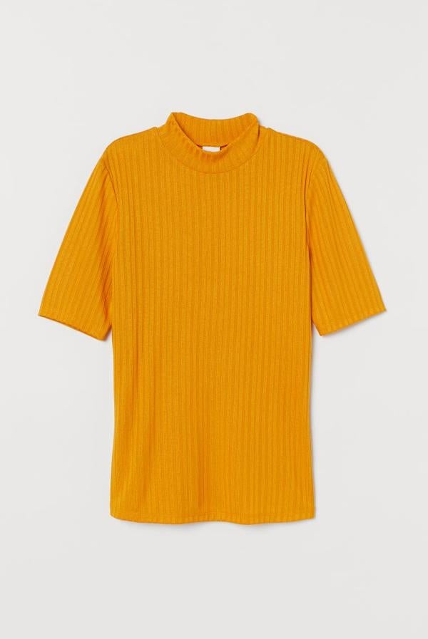 En amarillo huevo, con diseño entallado en punto de canalé, este top de H&M con cuello elevado y mangas cortas tiene un precio de 9,99 euros y está disponible entre las tallas S y XL.