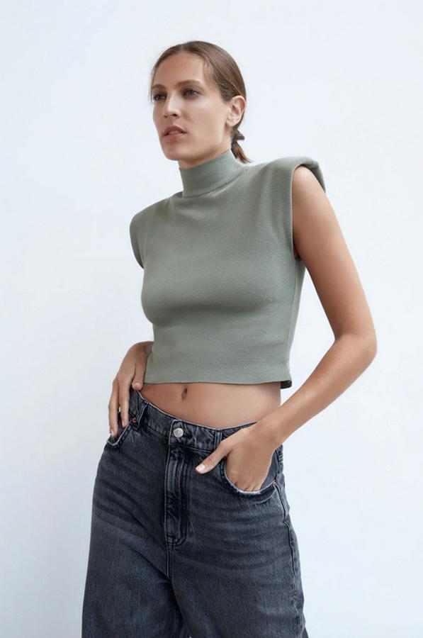 Con el detalle tendencia de la temporada, las hombreras, este top de punto de Zara en color caqui viene con manga sisa, cuello subido y diseño cropped. Cuesta 17,95 euros y está disponible entre las tallas XS y XL.