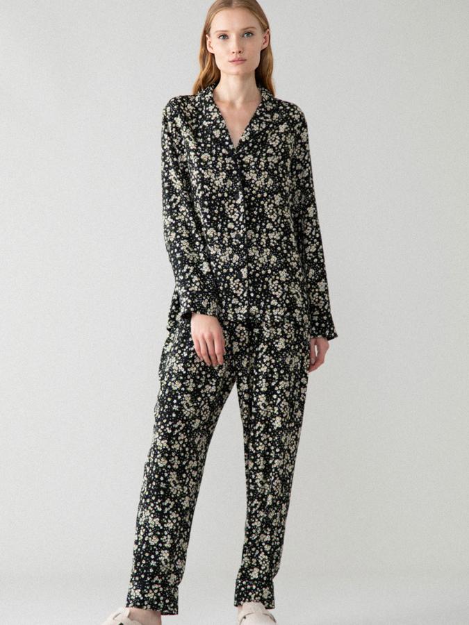 En color negro con estampado de flores pequeñas, este pijama está formado por una parte de arriba con solapa y botones y un pantalón ajustable con goma elástica y cordones. Tiene un precio de 12,99 euros.