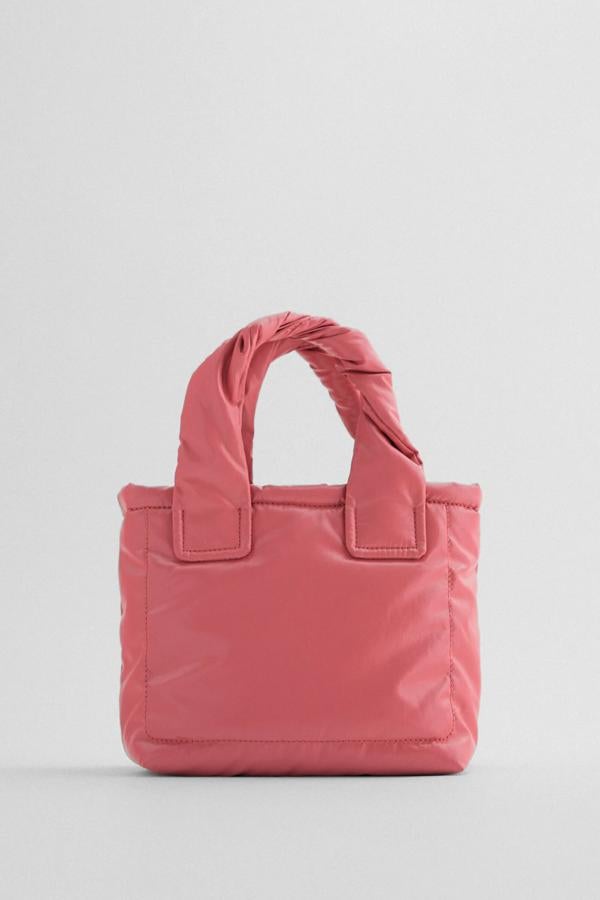 Disponible en rosa o en verde, este bolso formato mini shopper cuenta con cuerpo acolchado con pespuntes, asas de mano entrelazadas y asa de hombro ajustable y extraíble. Es de Zara y tiene un precio de 19,95 euros.