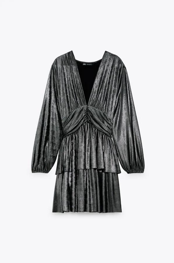 Escote de pico y manga larga abullonada para este vestido mini en color plata con detalle de frunce en la cintura y bajo con volantes. Tiene un precio de 39,95 euros y está disponible entre las tallas XS y XL.