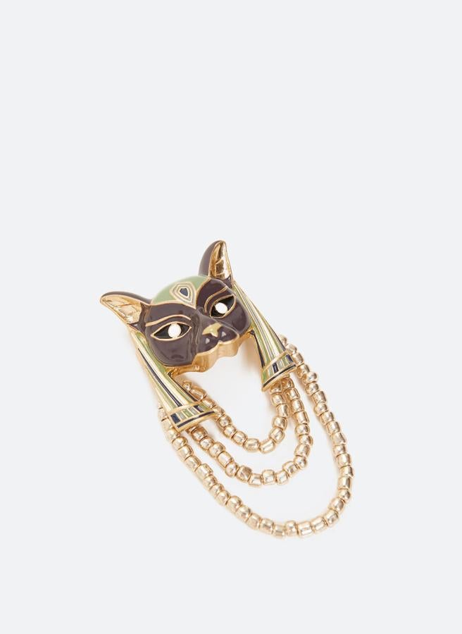 Esta cabeza tipo diosa egipcia esmaltada y dorada con cierre de aguja seguro es de Uterqüe y tiene un precio de 39 euros.