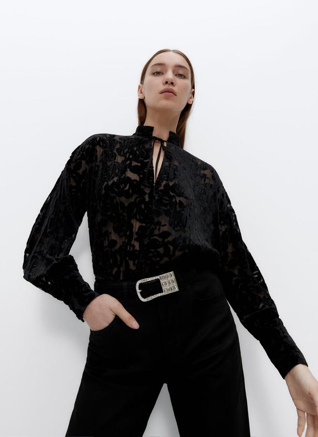 Confeccionada en un tejido devorado de flores, con cuello mao y lágrima en el centro delantero, esta camisa negra oversize y detalle de lazada en el escote cuesta 89 euros y está disponible en las tallas S y M.