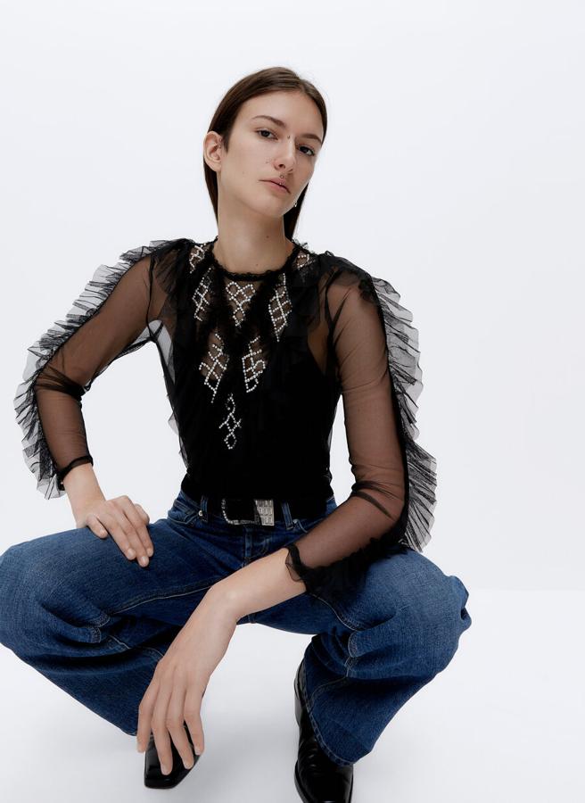 Con cuello redondo y mangas largas con volante, esta camiseta negra viene con delantero y espalda con detalle bordado en pedrería y volante y forro elástico de tirantes ajustable. Cuesta 69 euros y está disponible en las tallas S, M y L.