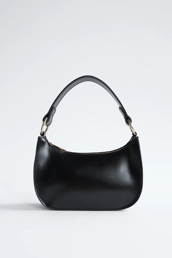Este mini bolso de piel en color negro y cierre con cremallera cuenta con asa de mano con detalles dorados y tiene un precio de 35,95 euros. Es de Zara.